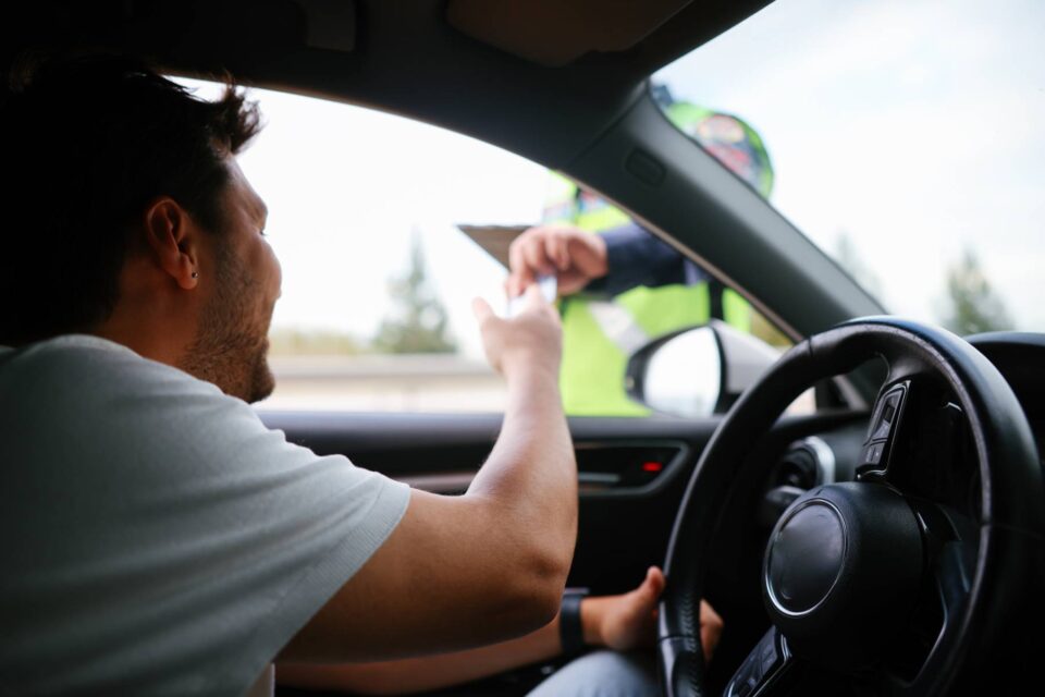 Police officer conducting a breathalyzer test on a driver in his car