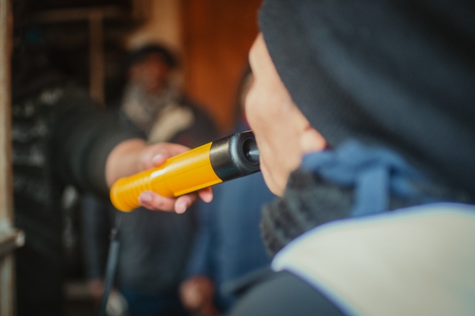 Person undergoing a breathalyzer test with a handheld yellow device